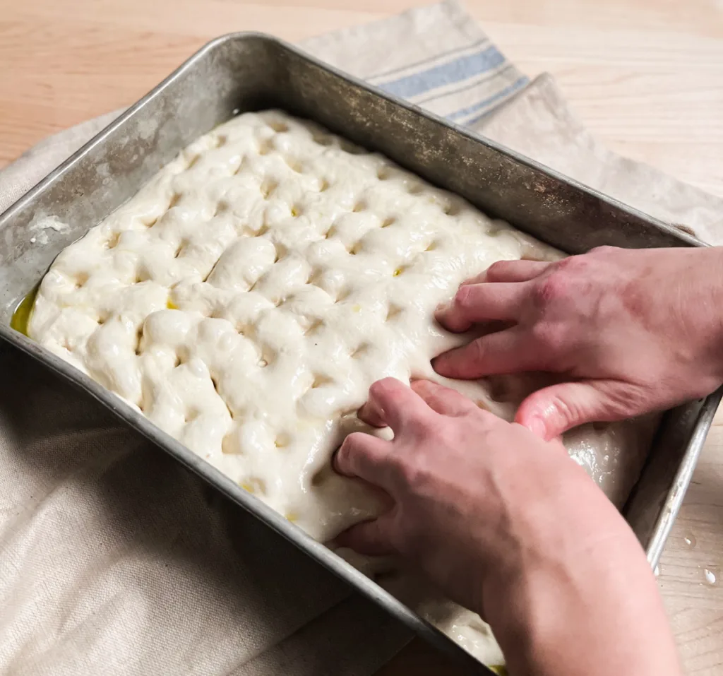 Dimpling the focaccia dough.