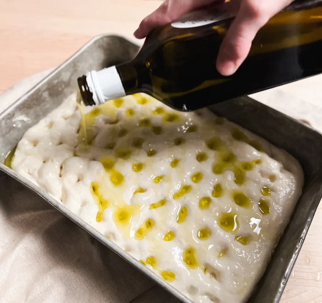 drizzling olive oil over the dough.