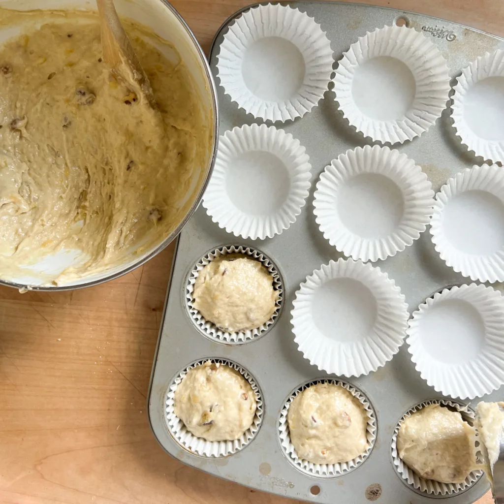 adding muffin batter to muffin pan