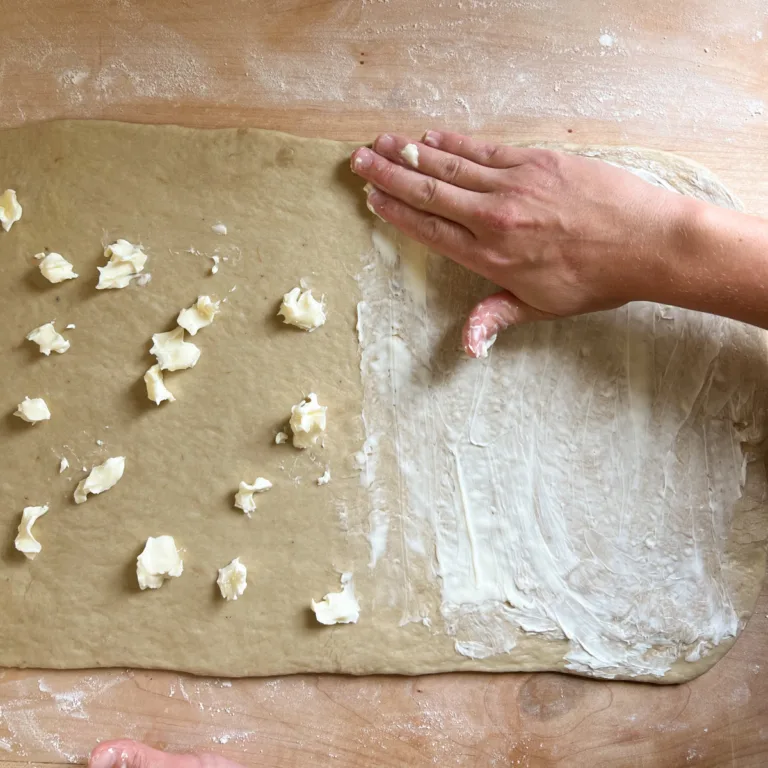 spreading butter onto the sheet of dough