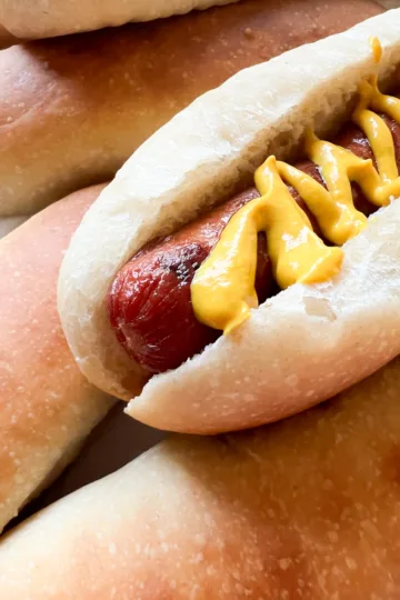 a hot dog in a sourdough hot dog bun topped with mustard.