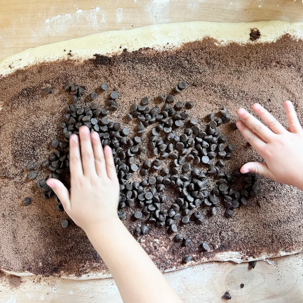 spreading chocolate chips onto the sweet dough
