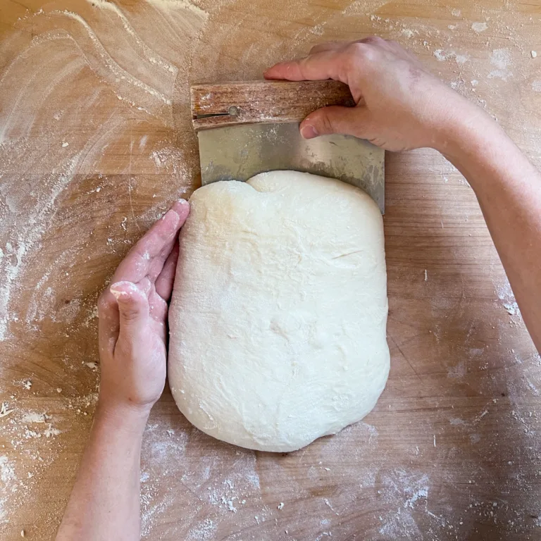 Shaping the dough by folding the top portion into the center.