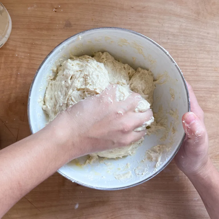 Mixing the dough by hand to fully incorporate the ingredients.