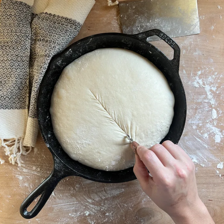 Scoring the sourdough skillet country loaf with a razor blade.