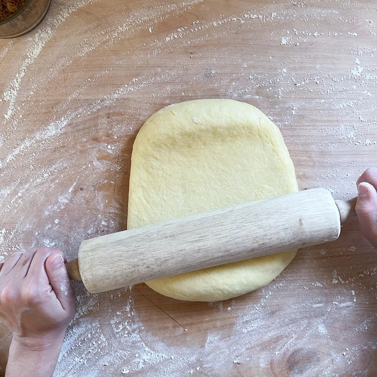 Brioche dough being rolled out with a rolling pin.