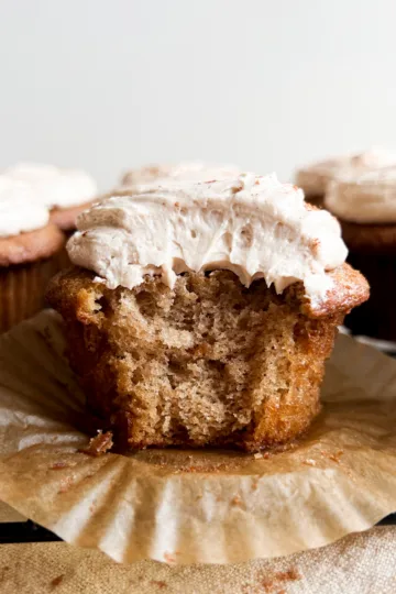 A cinnamon cupcake with a bite taken out of it.