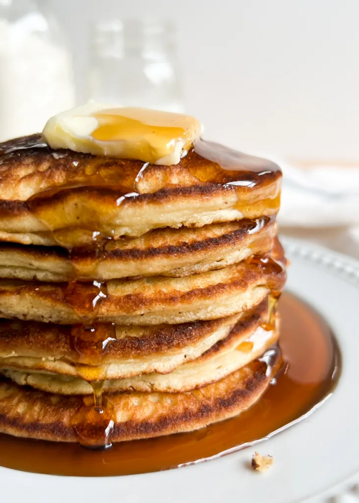 A stack of sweet cream pancakes with syrup on them.