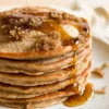 A stack of cinnamon brown sugar pancakes with maple syrup on top.