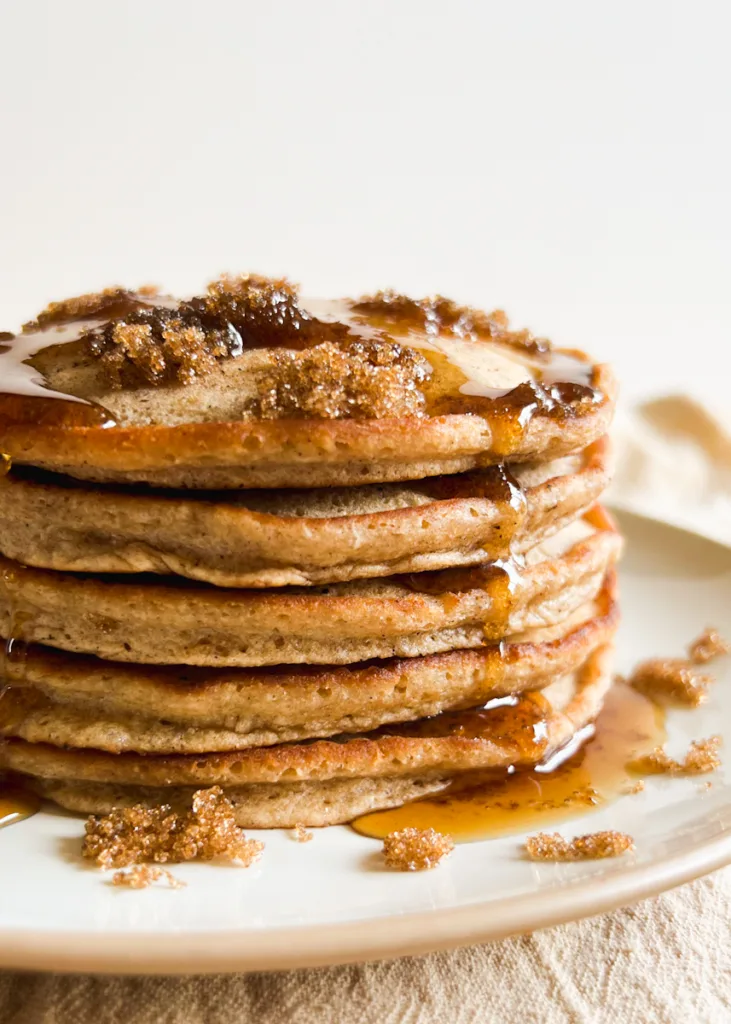 A stack of cinnamon brown sugar pancakes with syrup drizzling down the sides.