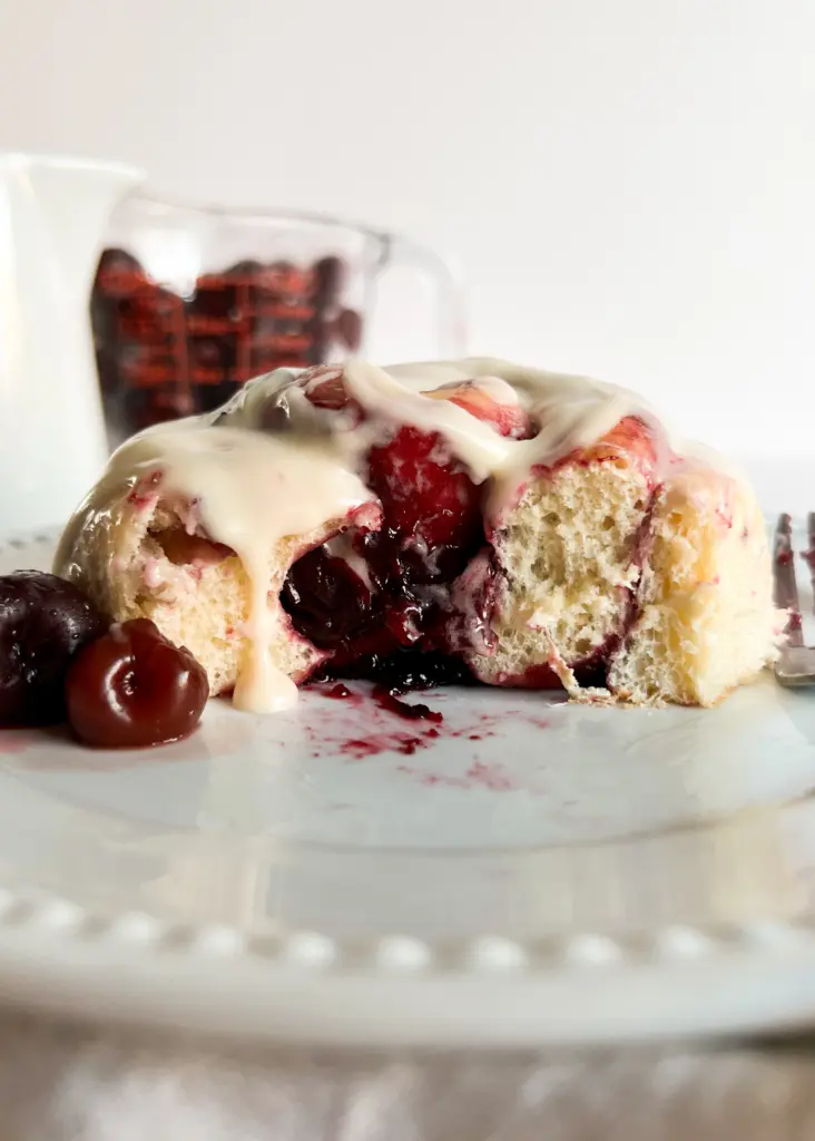 a cherry cinnamon roll with a bite taken out of it.