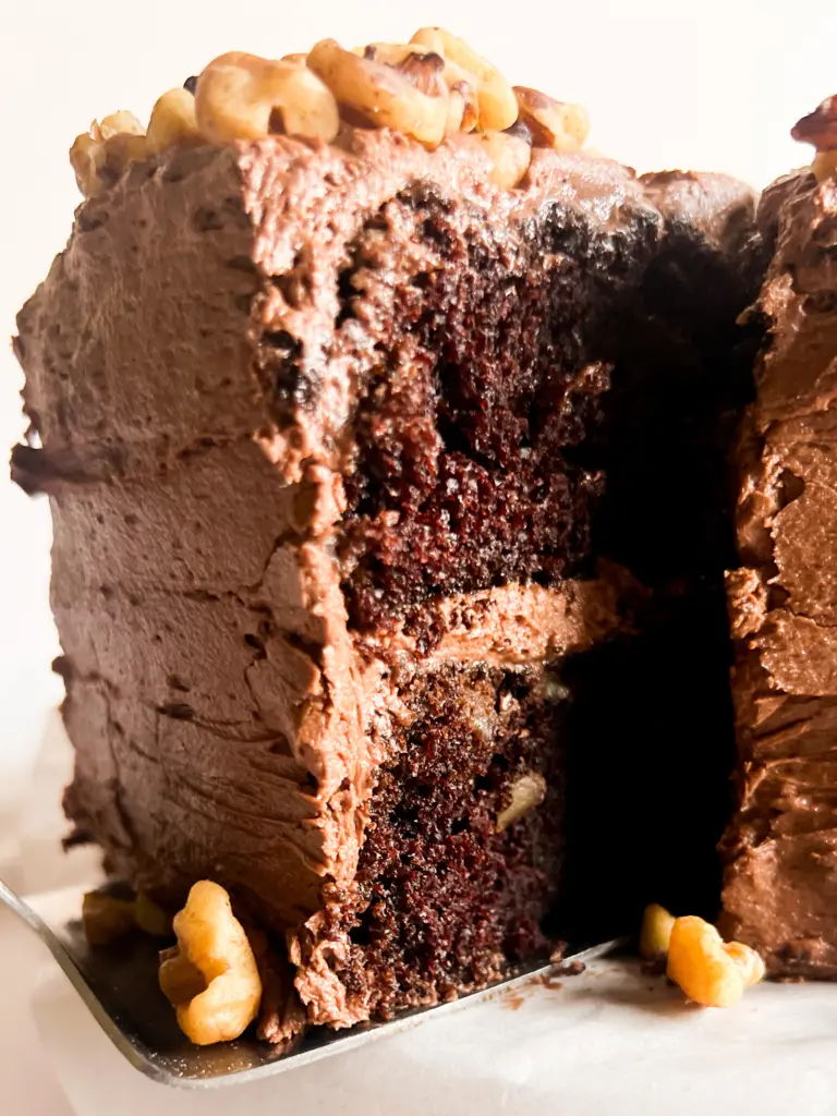 A slice of chocolate walnut cake being cut from the whole cake.