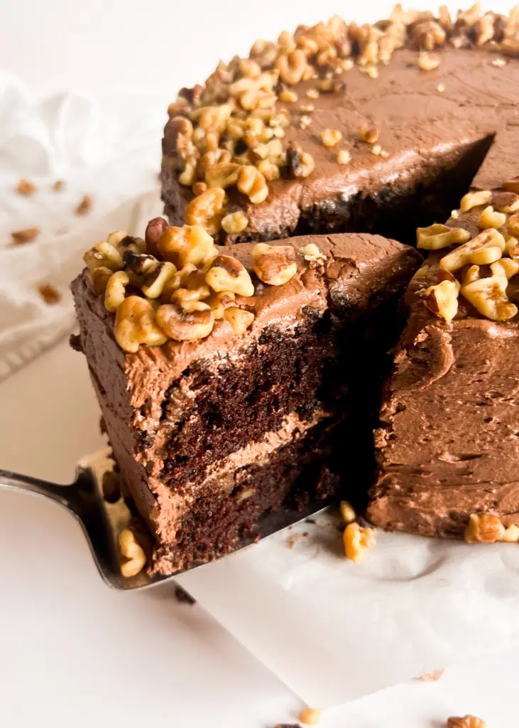 A slice of chocolate walnut cake being cut from the whole cake.