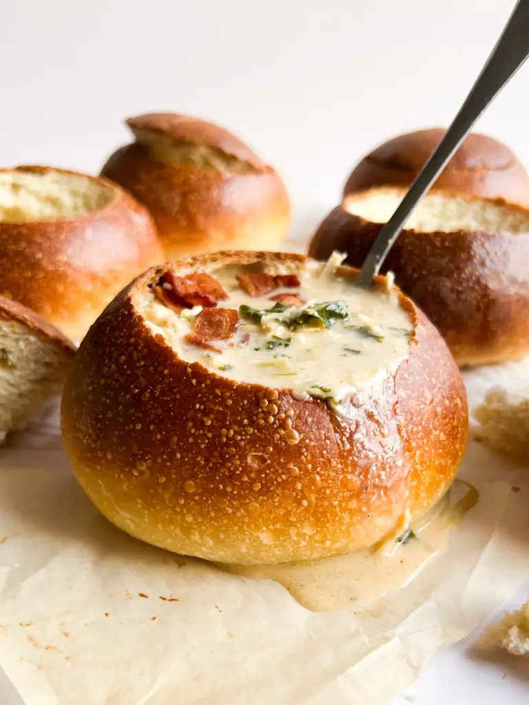 A sourdough bread bowl filled with creamy chicken soup.