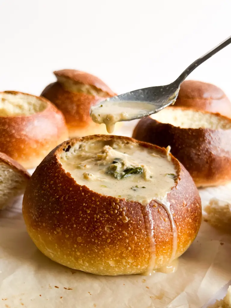 A sourdough bread bowl filled with creamy chicken and kale soup.