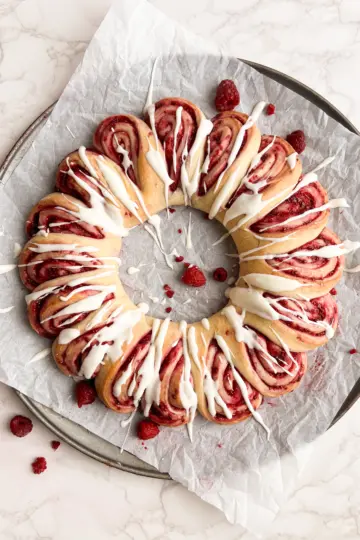 A sourdough raspberry roll wreath on a baking sheet.