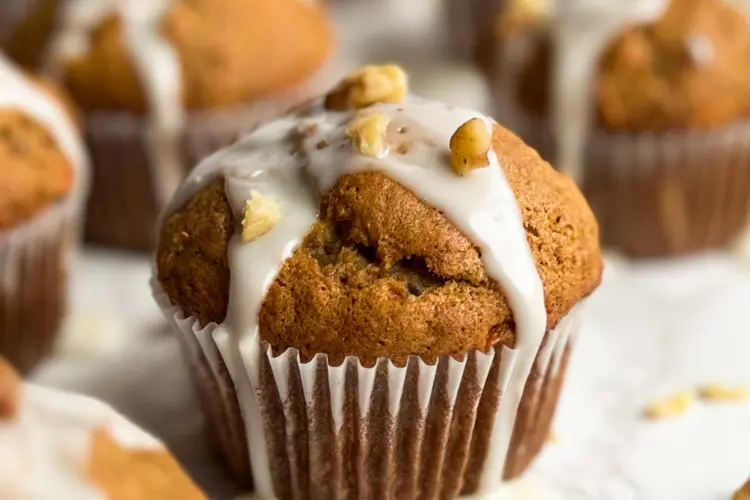 Banana carrot muffins with a simple vanilla glaze and walnuts on top.