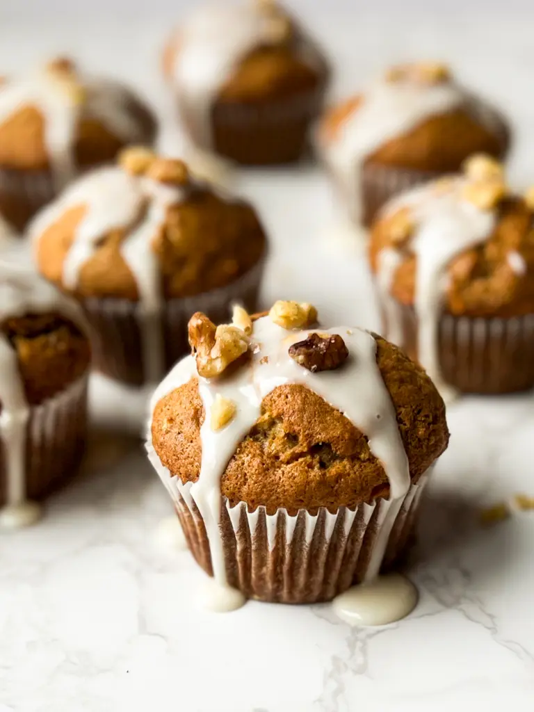 Banana carrot muffins with a simple vanilla glaze and walnuts on top.