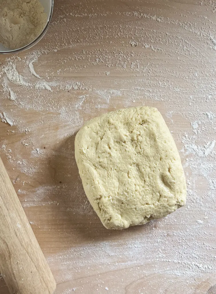 Soft sweet sourdough cinnamon roll dough turned out onto a floured work surface, ready to be rolled and shaped into cinnamon rolls.