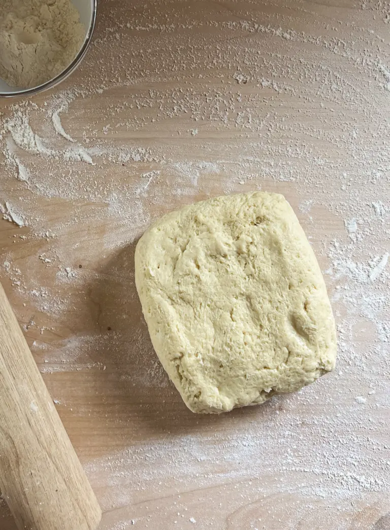 Soft sweet sourdough cinnamon roll dough turned out onto a floured work surface, ready to be rolled and shaped into cinnamon rolls.