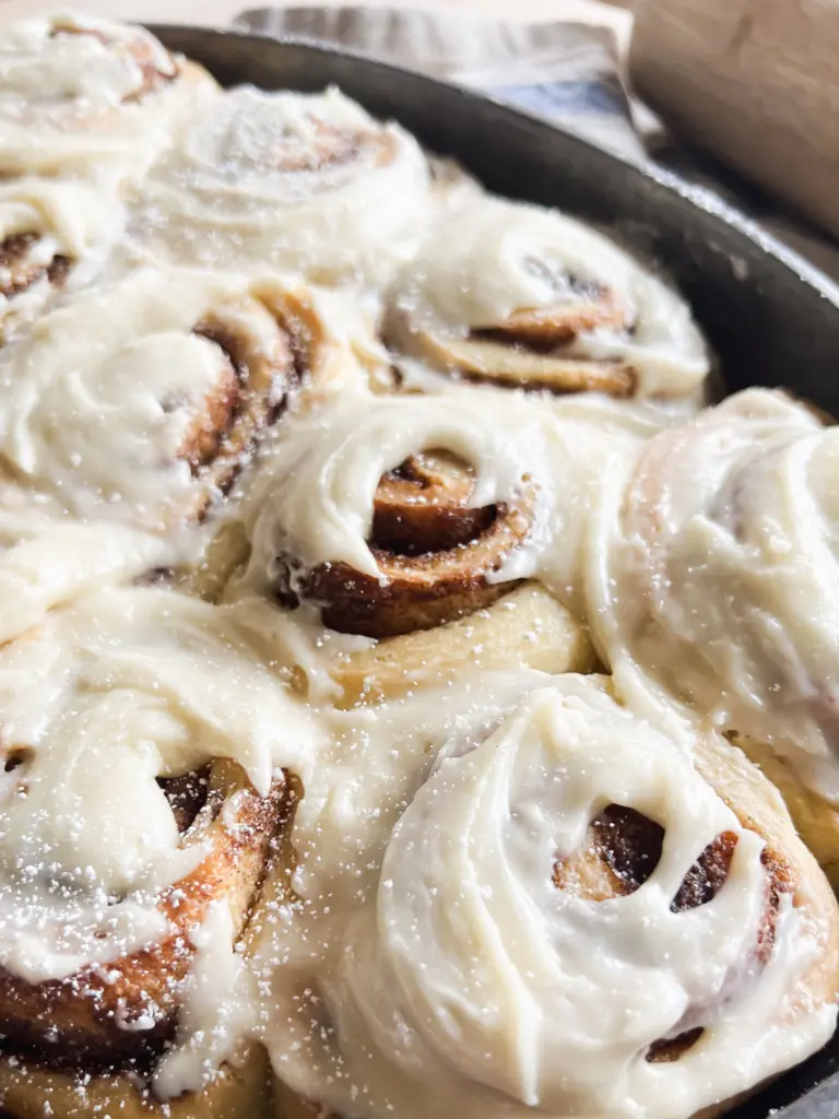 Freshly frosted sourdough cinnamon rolls in a pan, soft and fluffy, ready to be served for breakfast or brunch.