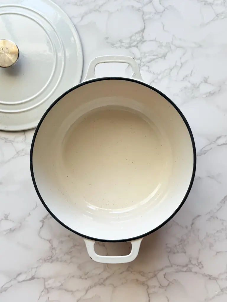 A white enamel Dutch oven after being cleaned that looks bright and new!