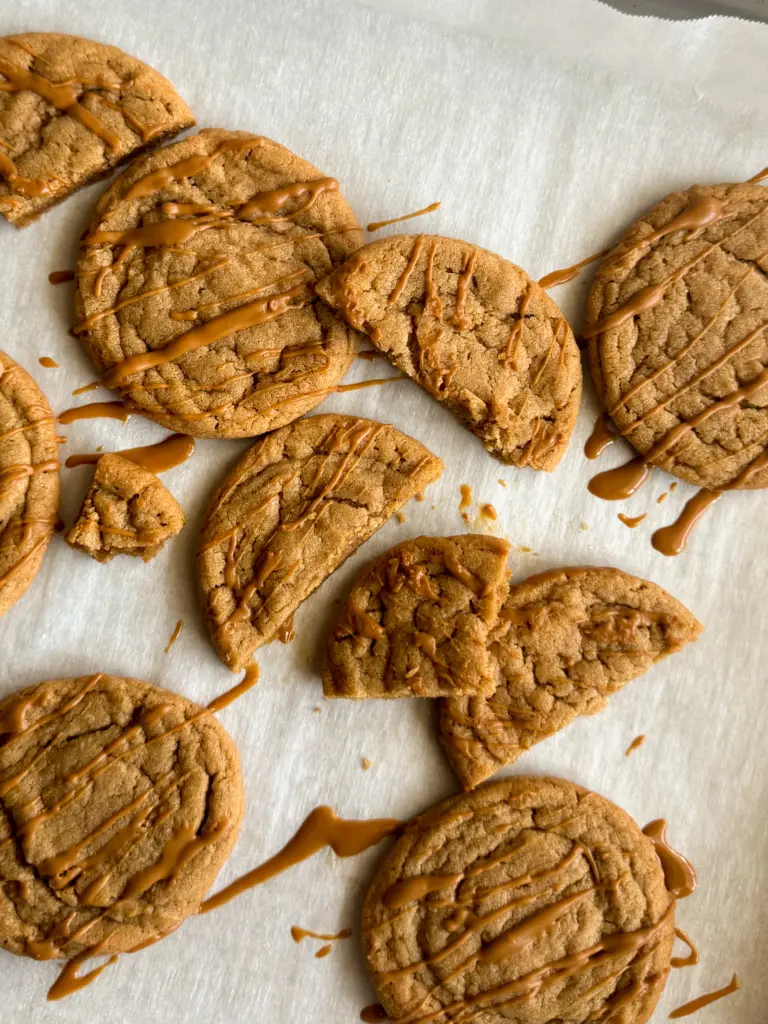 Overhead view of a batch of biscoff cookie butter cookies cooling on a parchment lined baking sheet.