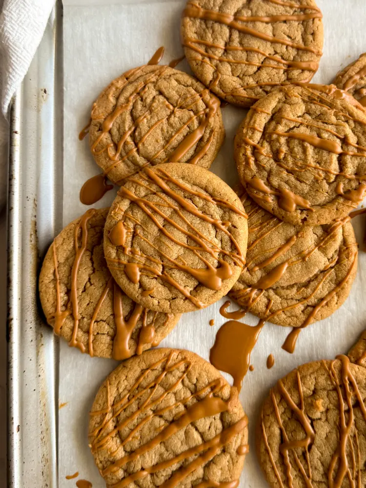 Overhead view of a batch of biscoff cookie butter cookies cooling on a parchment lined baking sheet.